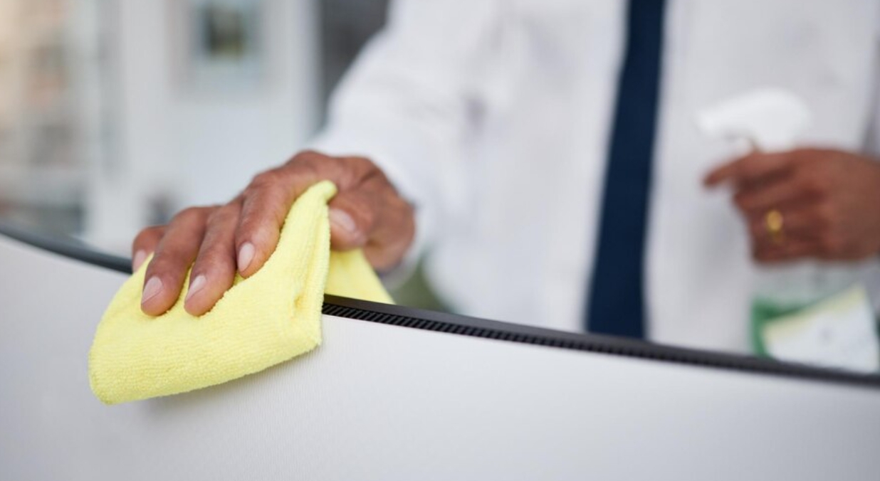 Person hands and cleaning computer with cloth in office